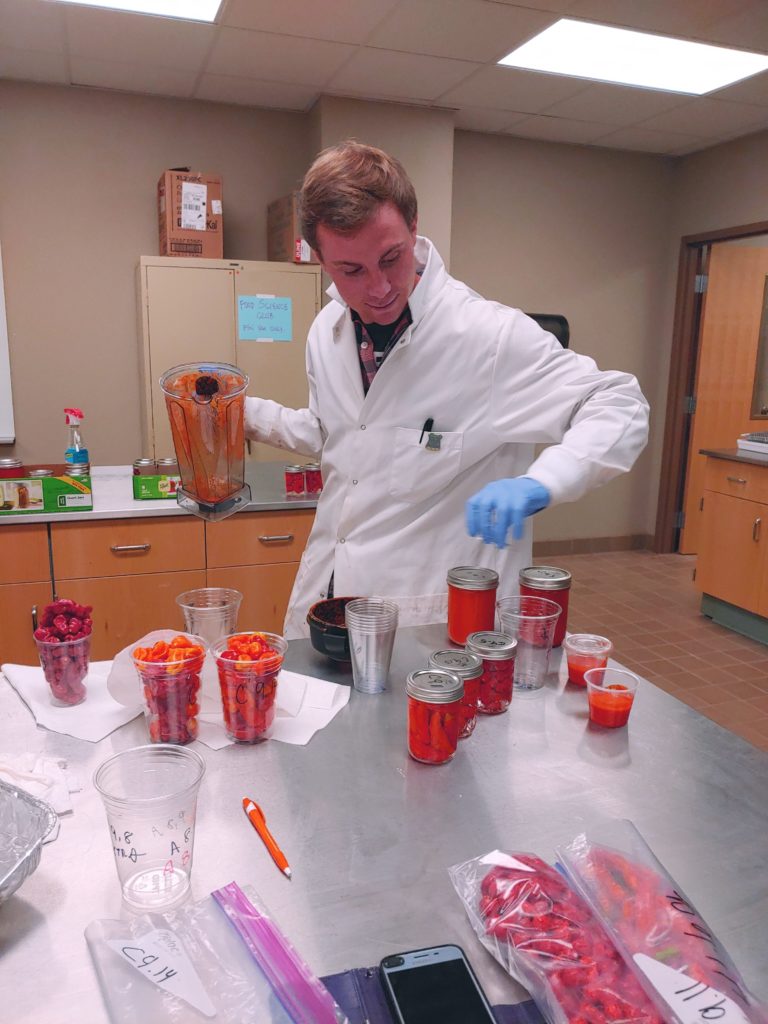 male student in lab processing red peppers 